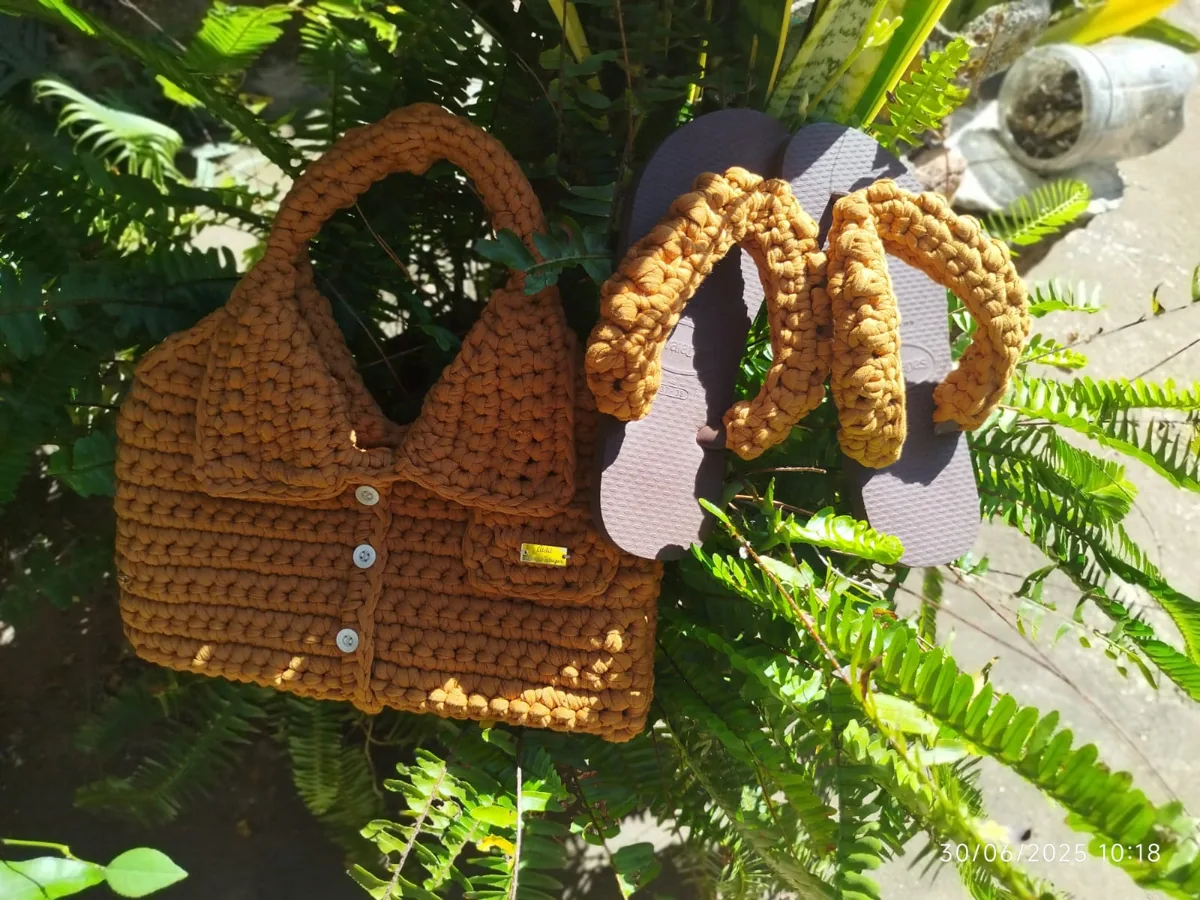 Bolsa e chinelos com detalhes em crochê dourado entre folhagens